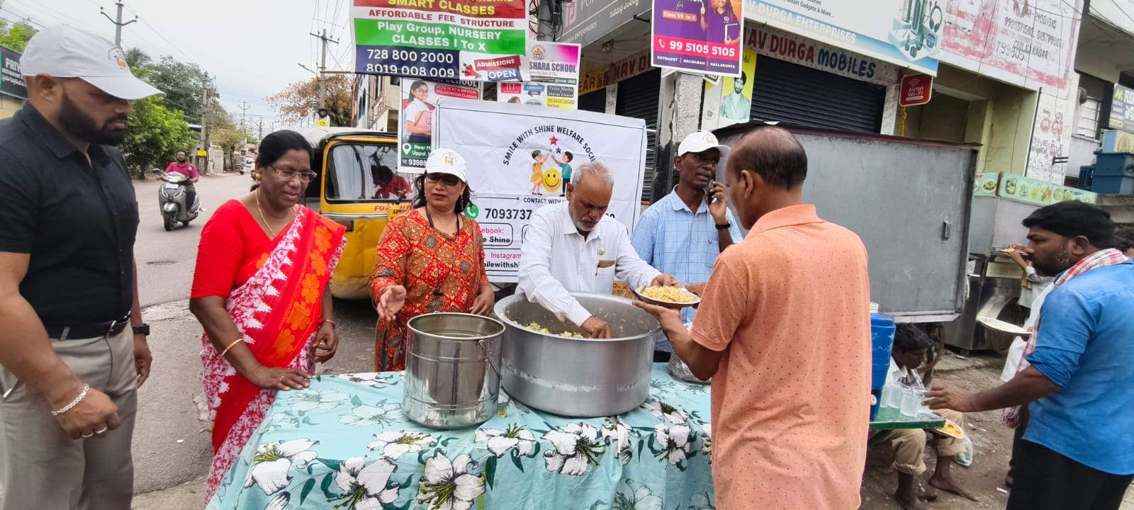People waiting on a pavement for the breakfast drive to reach them