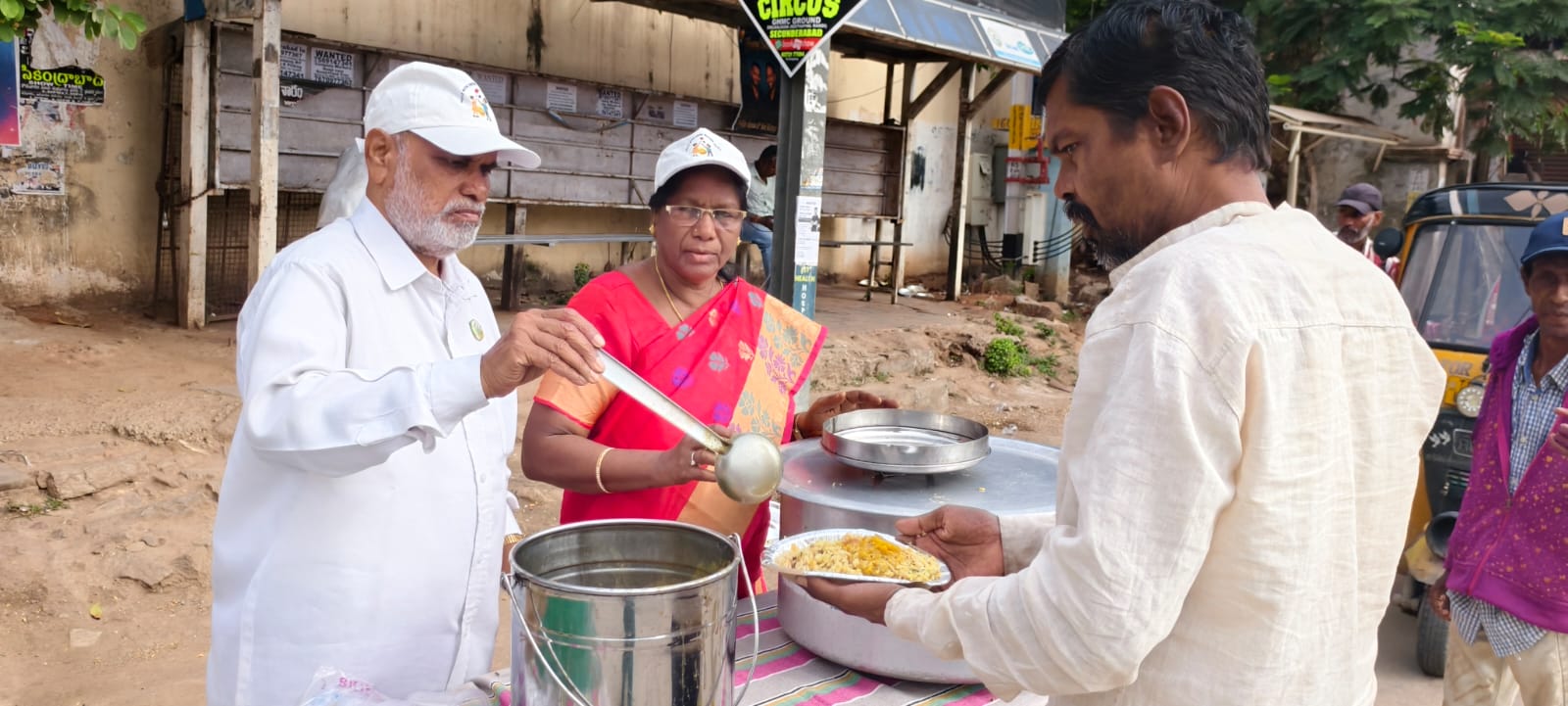 Senior team members of Smile With Shine serving warm meals to an elder on the roadside