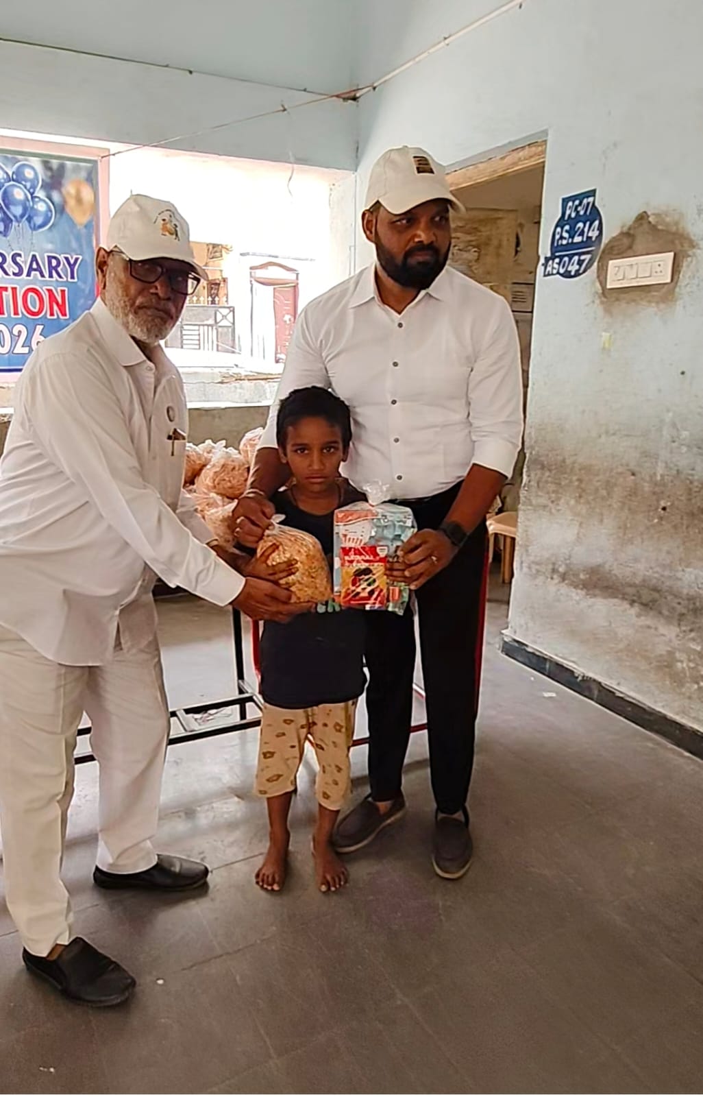 A young child receiving a stationery kit and food pack from the Smile With Shine senior team at the 1st Anniversary drive